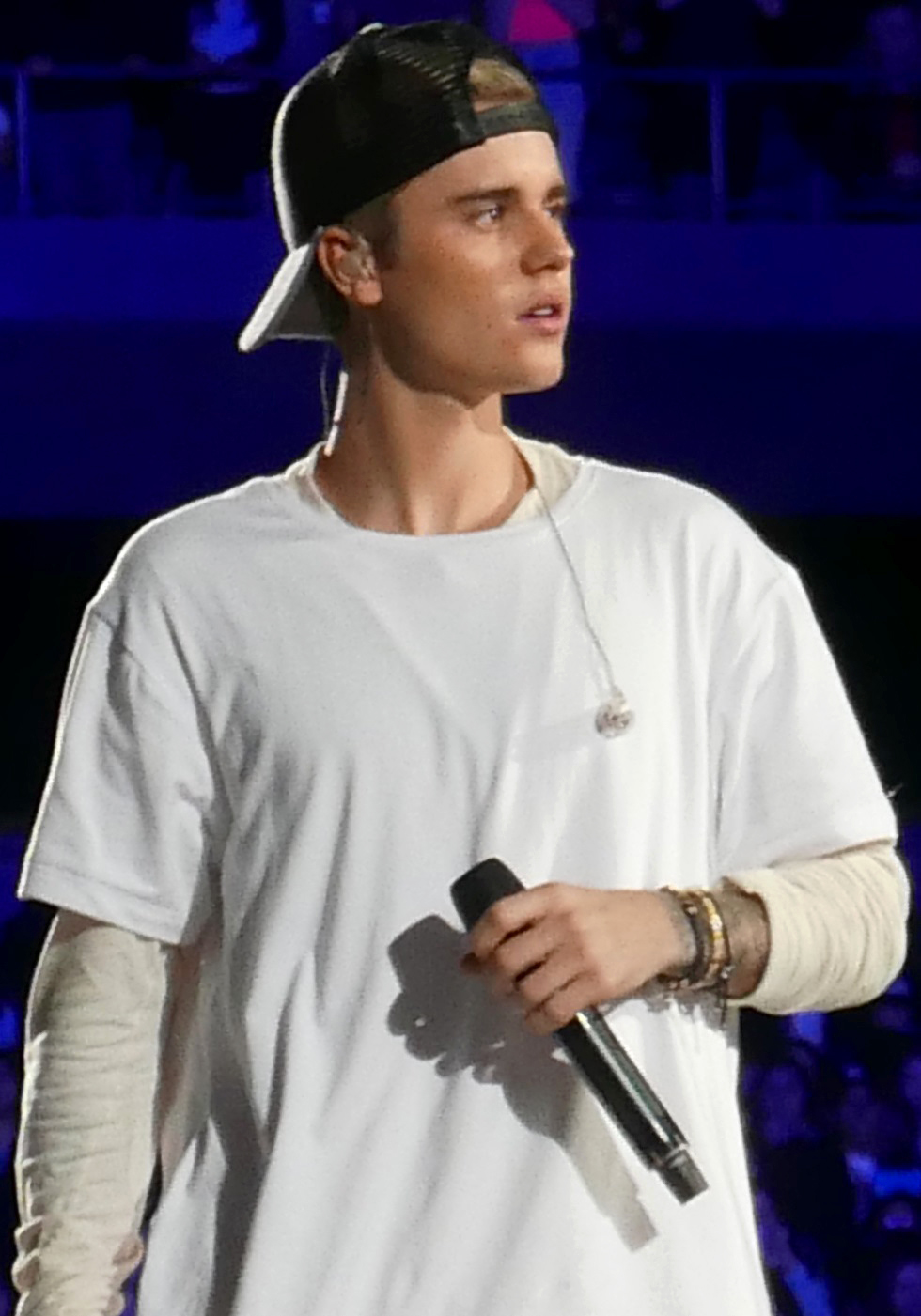 Justin Bieber performing in a white shirt and black cap in 2015