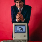 Steve Jobs sitting with the original Macintosh computer in 1984