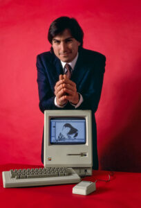 Steve Jobs sitting with the original Macintosh computer in 1984