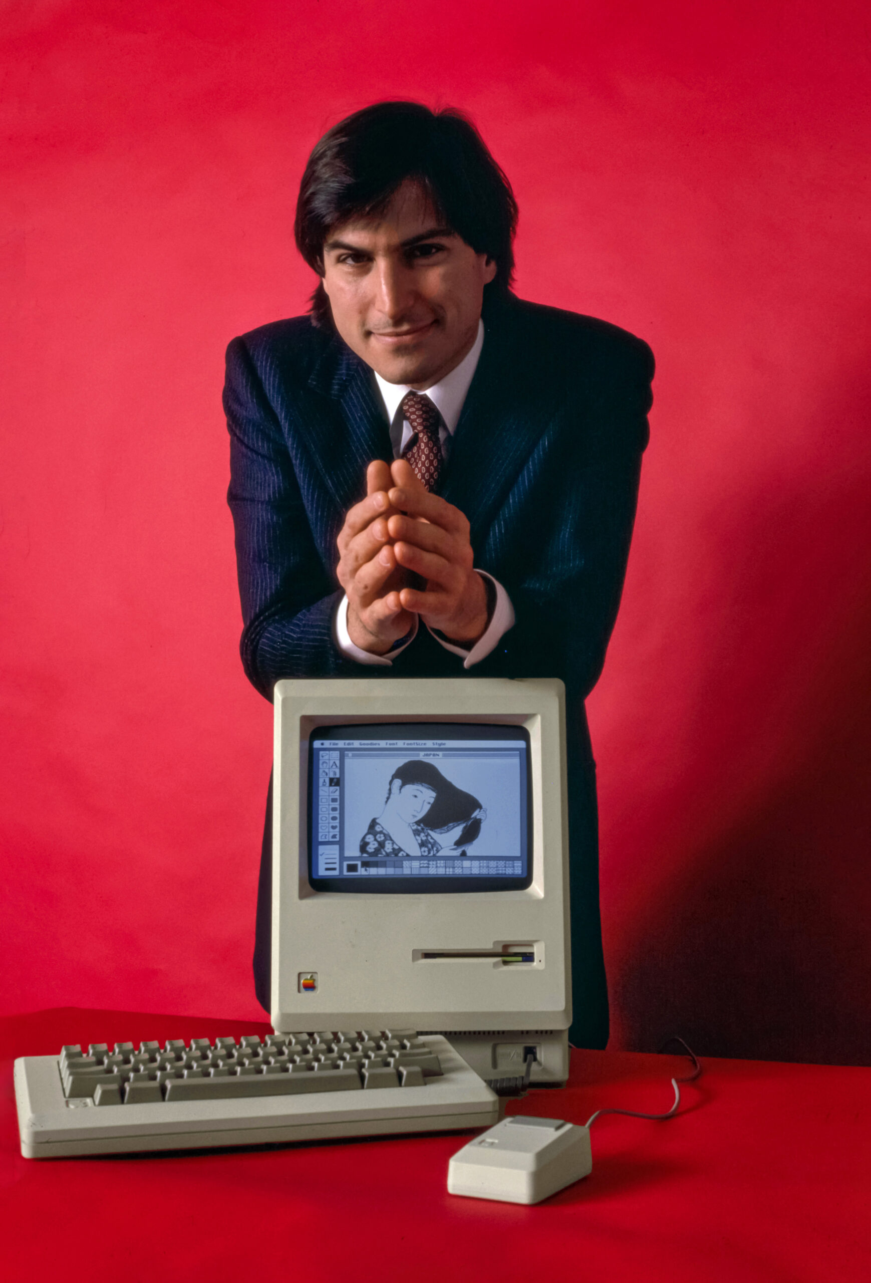 Steve Jobs sitting with the original Macintosh computer in 1984